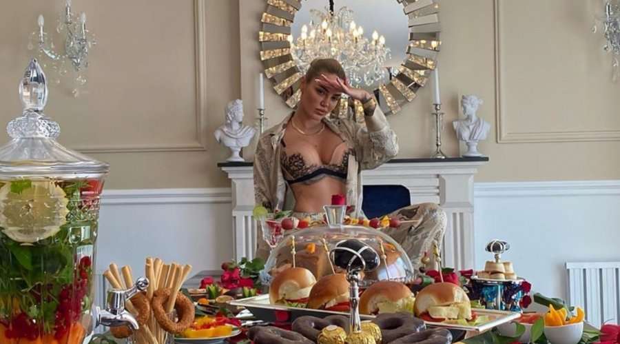 Morena pozon pranë tavolinës plot, përmend lokacionin duke sharë